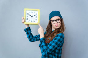 Hipster woman pointing finger on wall clock