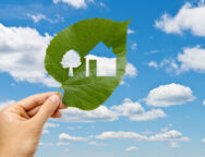 Hand holding leaf with a house cutted against sky